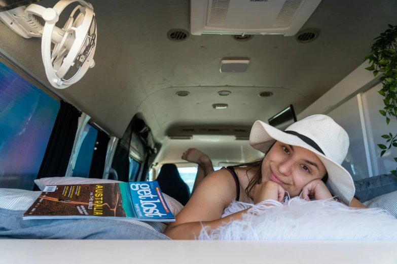 a girl in a hat laying on the bed of a vehicle