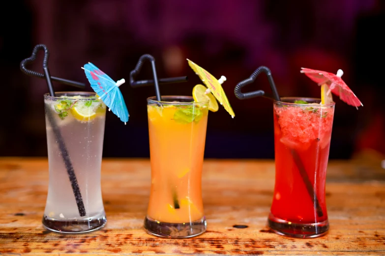 three different cocktails that have umbrella shaped straws