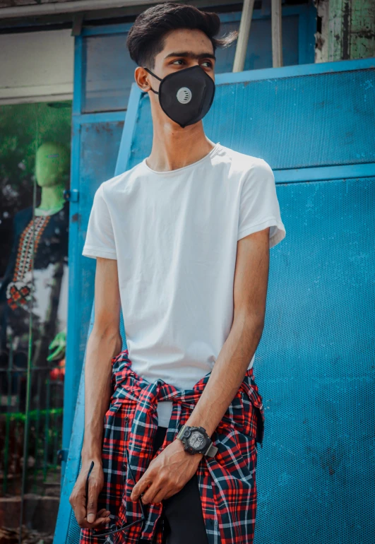 a man wearing an oversize cloth face mask in front of blue door