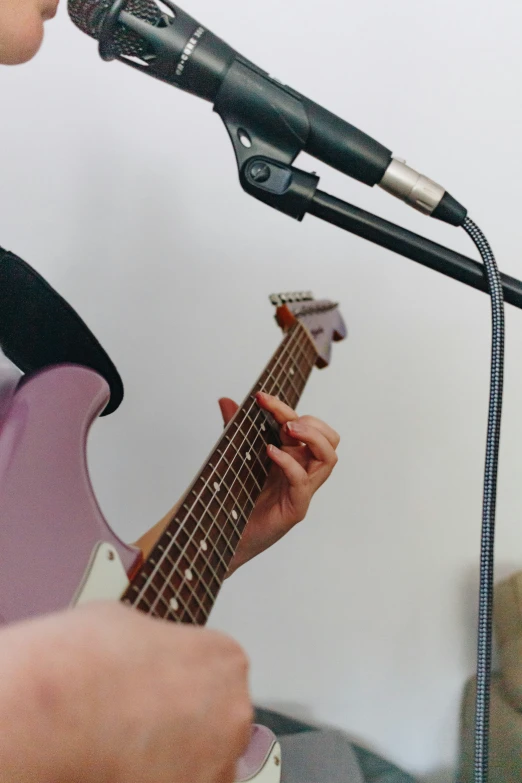 a man playing a guitar and singing into a microphone