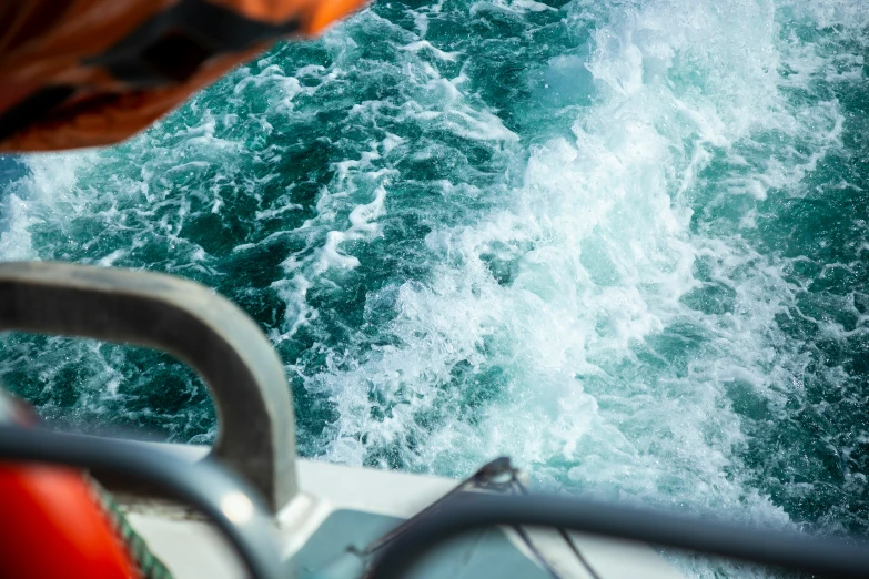 view from the back of boat on rough, green waves