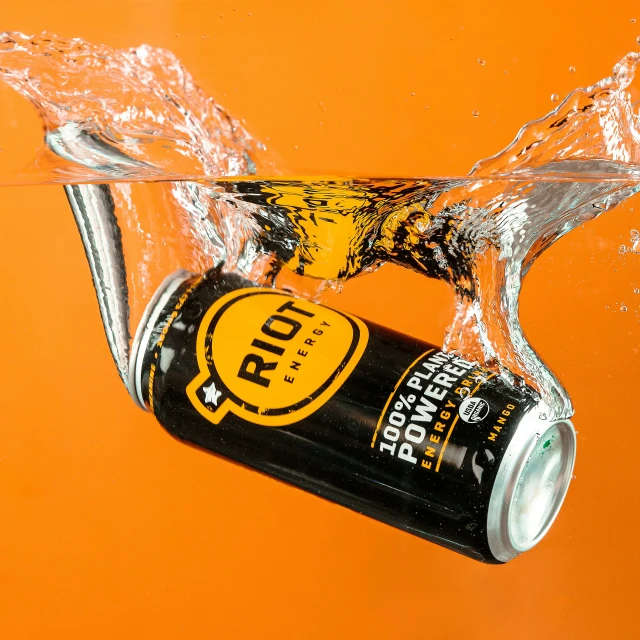 an orange background with a can of beer being poured from a faucet
