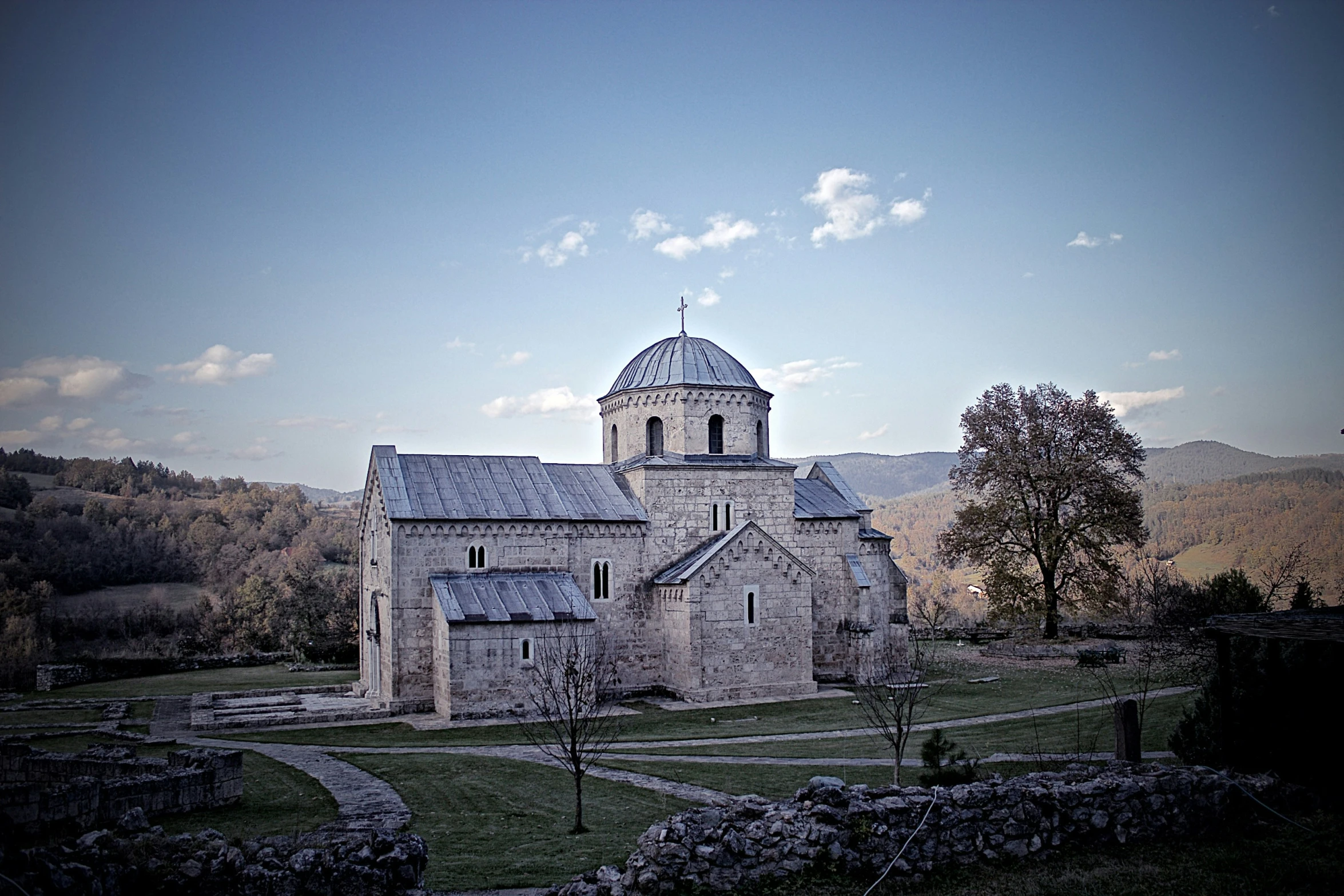 a tall stone church in the middle of a lush green valley