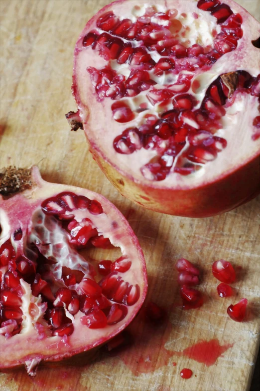 two pomegranates cut in half on a  board