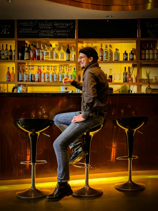 a man sitting on three stools at a bar