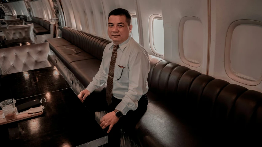 a man standing in an airplane cabin in his shirt and tie