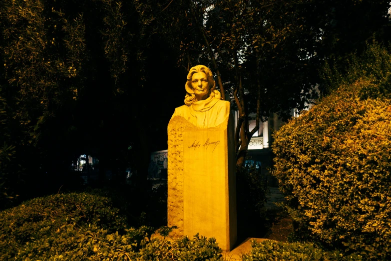 a statue of a woman surrounded by shrubs