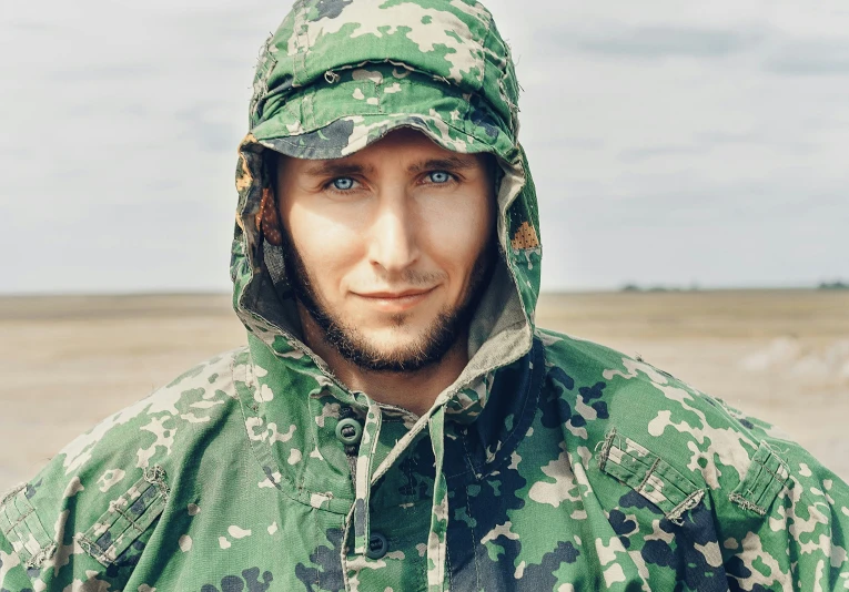 a man is dressed in a camouflage coat and hood