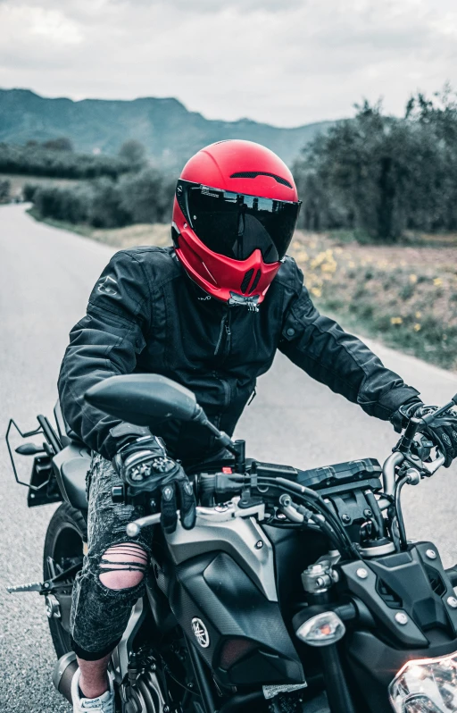 a person in black jacket and red helmet on motorcycle