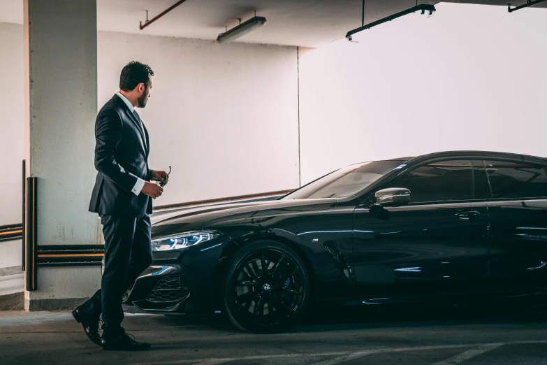 a man in a suit and shoes walking next to a car