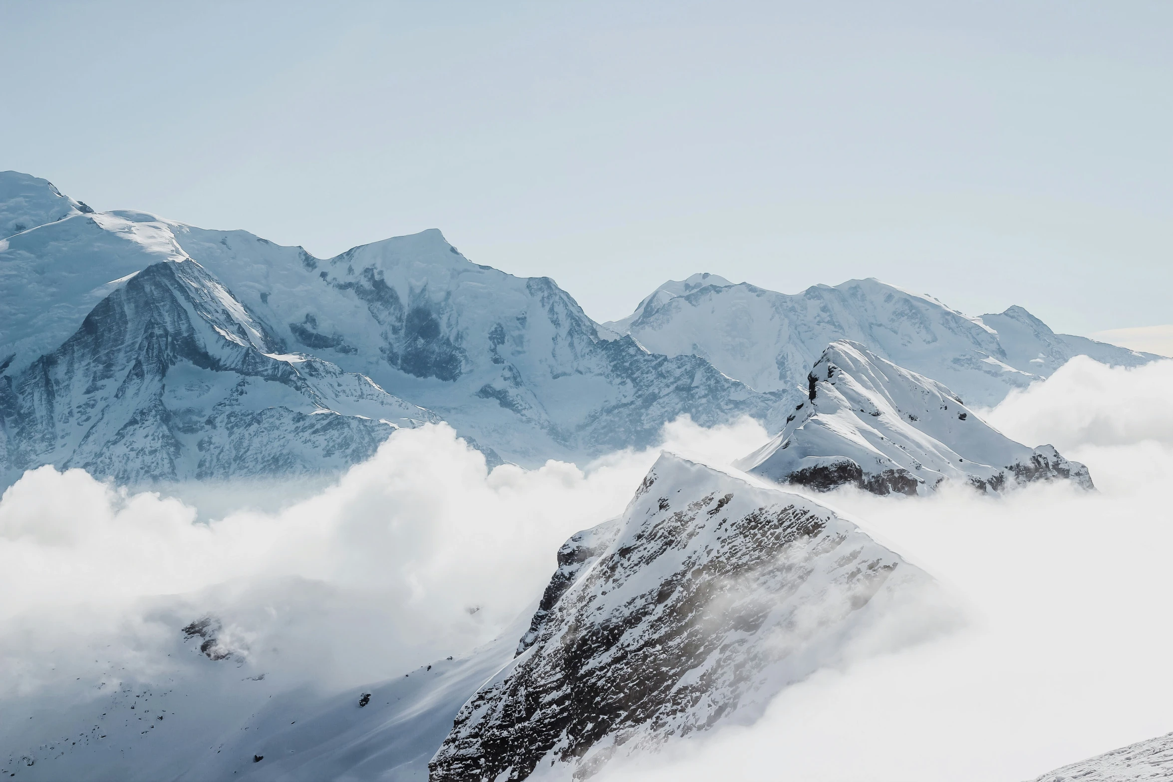 mountains rise high above clouds below them