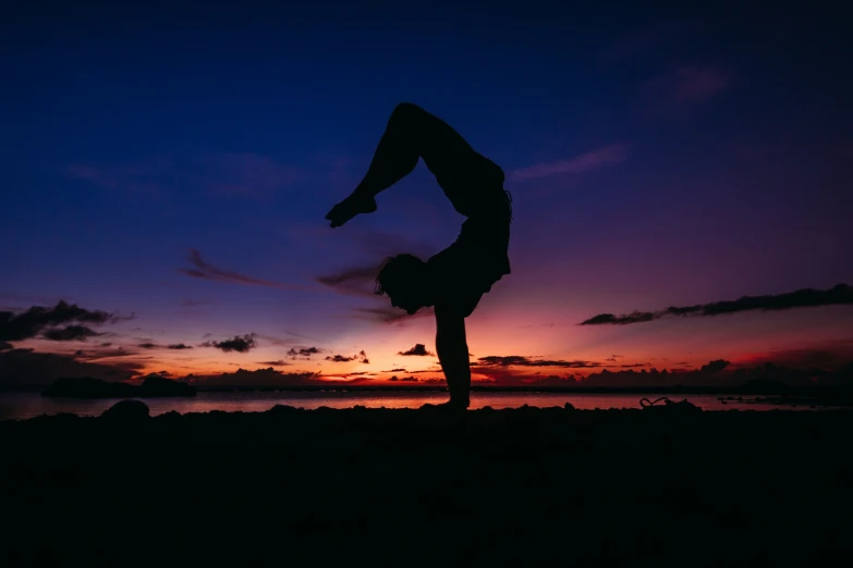 a man doing a handstand on the beach