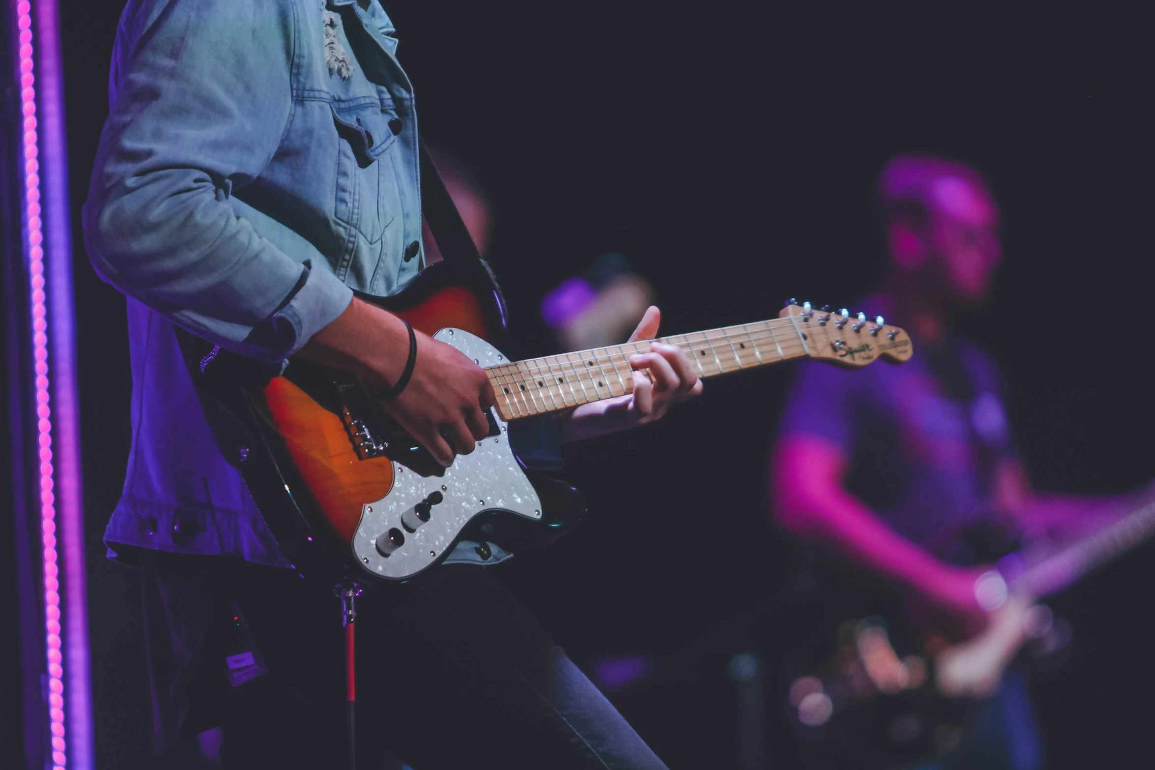 a man playing guitar on stage while others watch