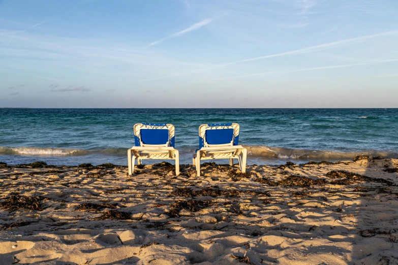 two empty beach chairs are on the sand by the ocean