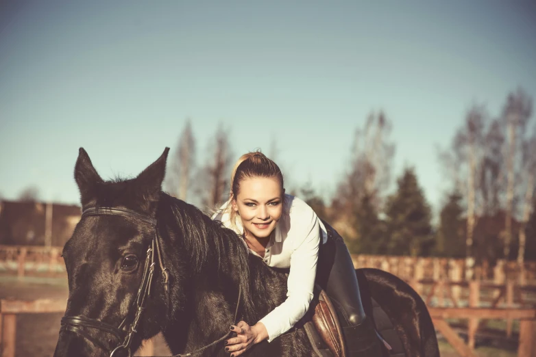 the woman is standing with her horse near fence