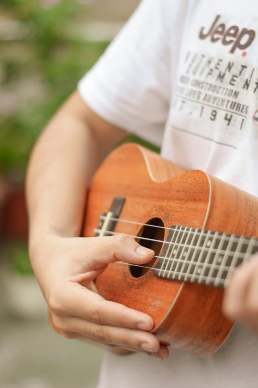 a person playing the ukulele with a guitar strap on his left shoulder