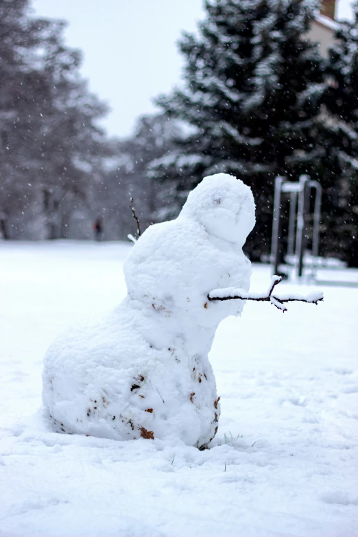 a snow man holding a stick and laying on the ground