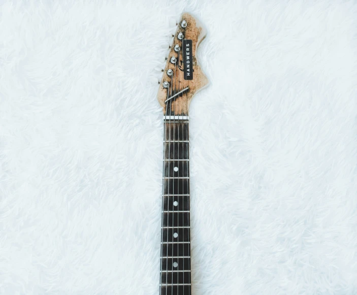 an electric guitar laying on top of a white blanket