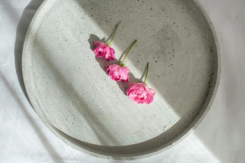 three pink roses are sitting in a bowl