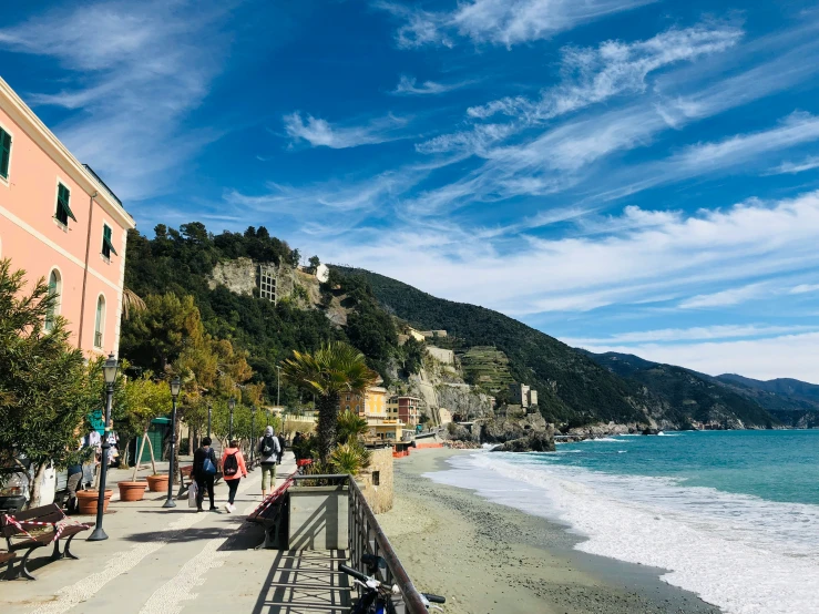 a sandy beach with a crowd of people walking on the shore