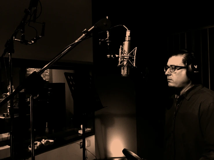 a person with headphones stands in front of a microphone