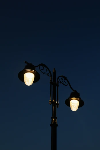 lamppost with street lights, and blue sky in background