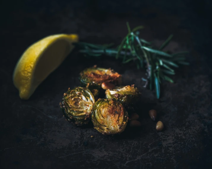 a piece of lemon sitting next to roasted artichokes