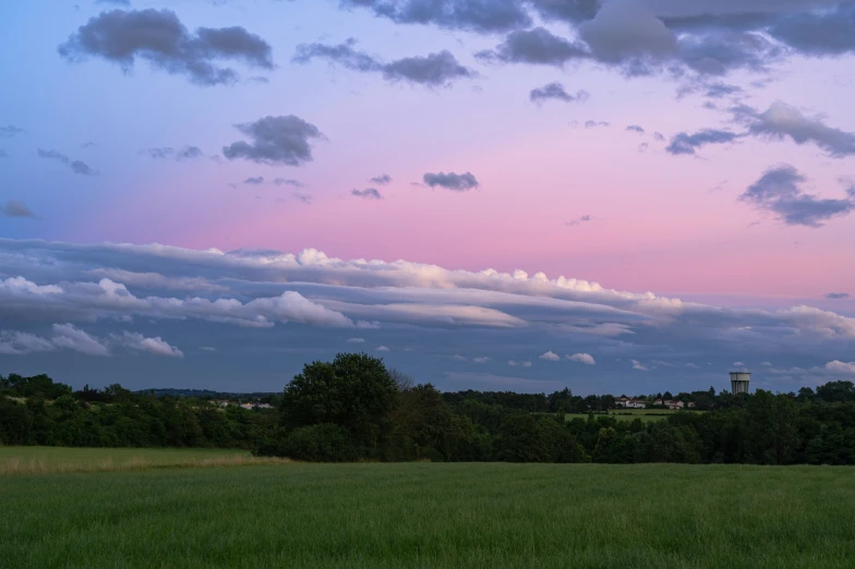 a large field full of grass and a lot of clouds