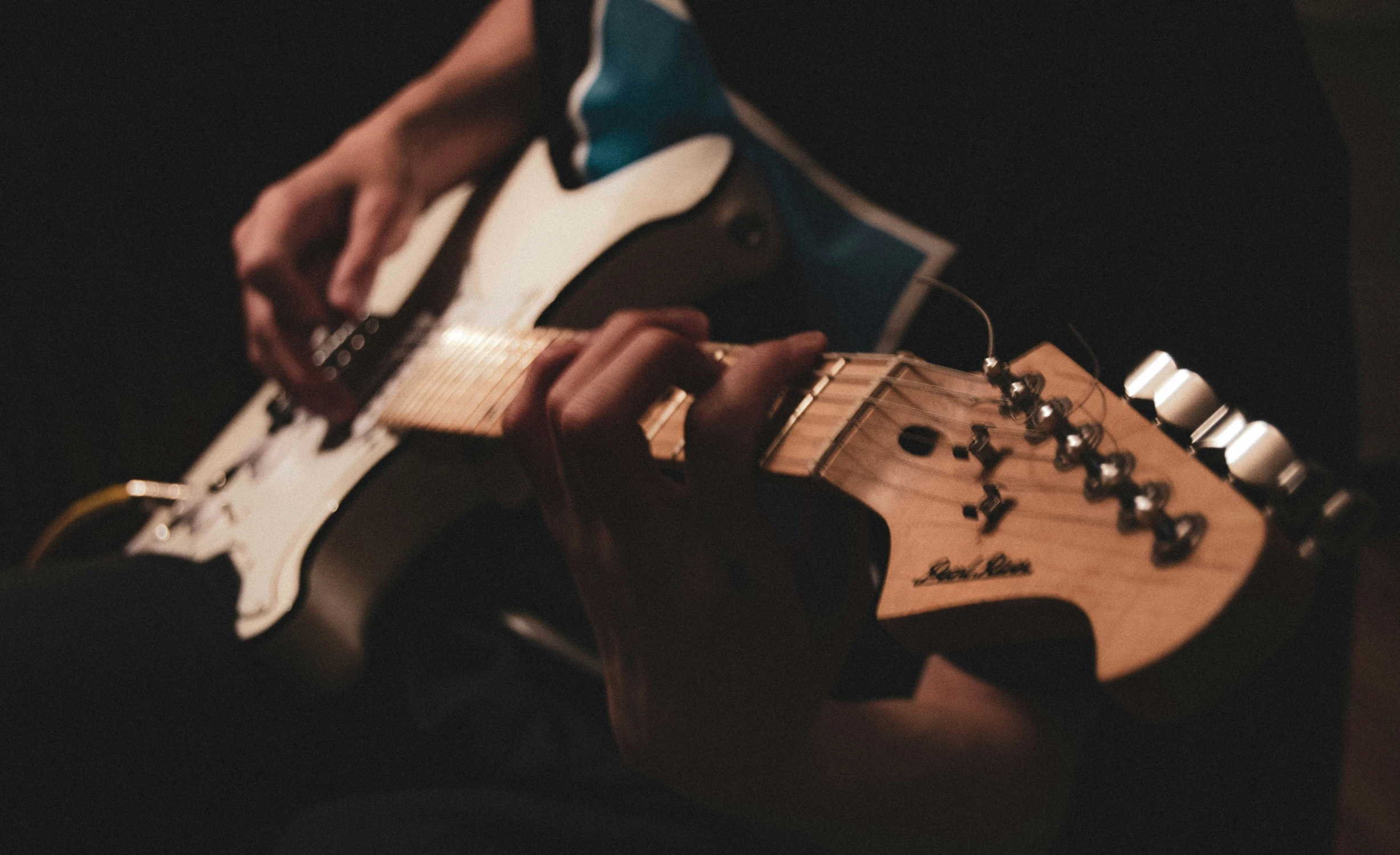 person playing an electric guitar with a wooden body