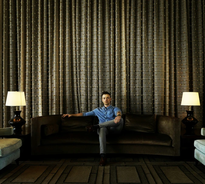 a man sits on a couch in a room with dries on the walls