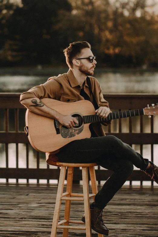 a man sitting on a stool holding a guitar