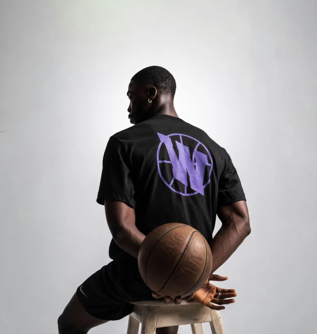 a man sitting on top of a stool holding a basketball