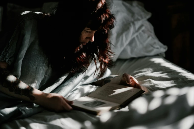 the woman is reading in bed under the blankets