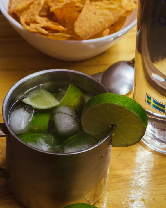 limes and ice in a metal mug next to chips