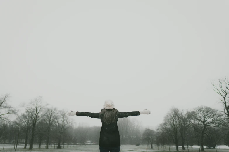 woman standing alone in snow with arms wide open