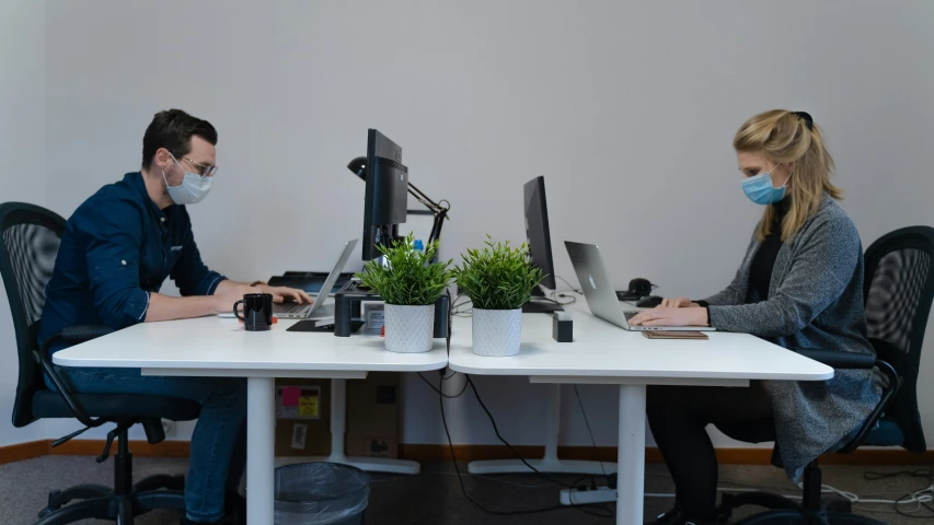 a man and woman sitting at a table working on computer screens