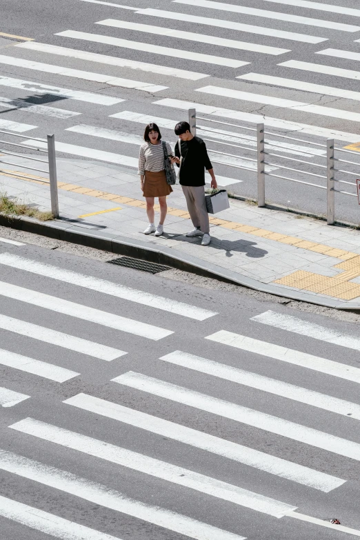 two people stand on a street corner near a crosswalk