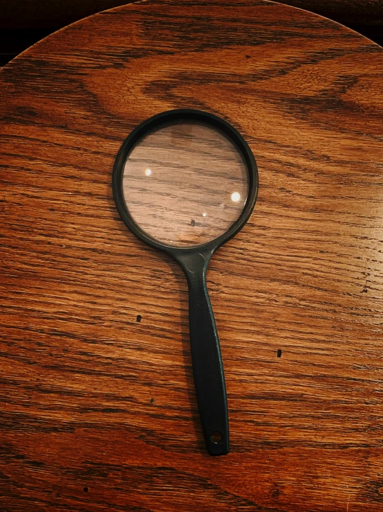 a magnifying glass on a wooden surface with its reflection