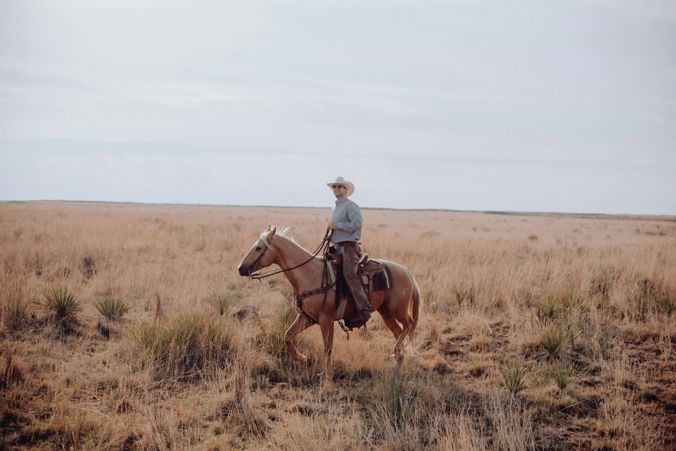 a man on a horse riding through an open field