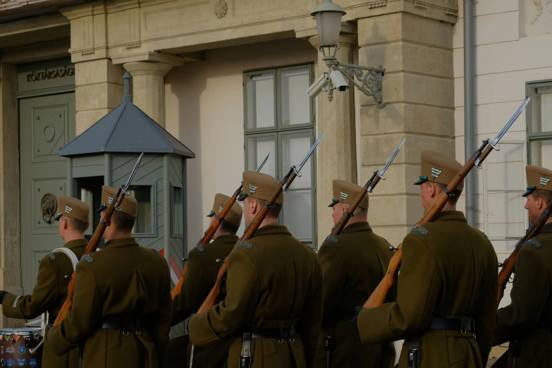 men in uniforms, one with hat and two with swords standing outside of a building