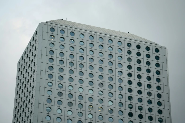 a tall gray building sitting underneath a cloudy sky