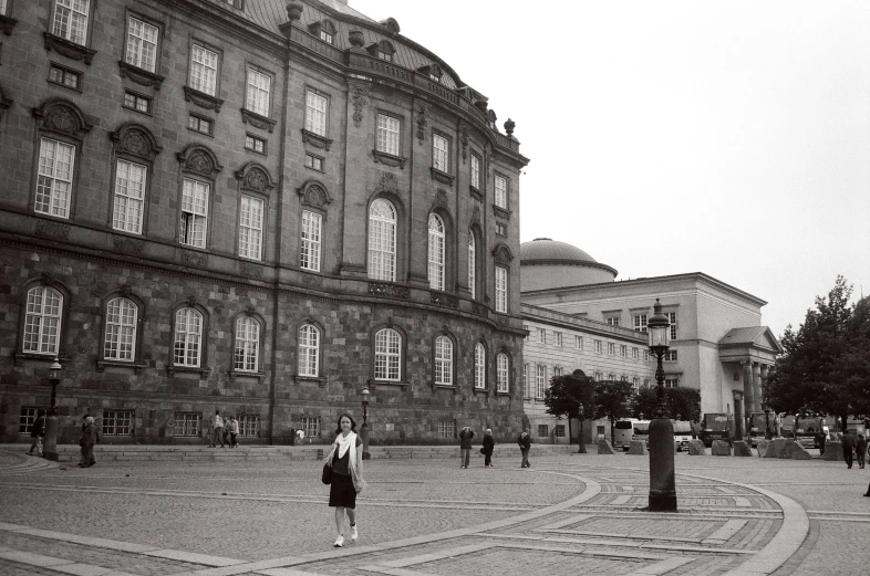 people walking along a walkway near an old building