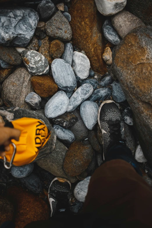 a person wearing orange shoes standing by rocks