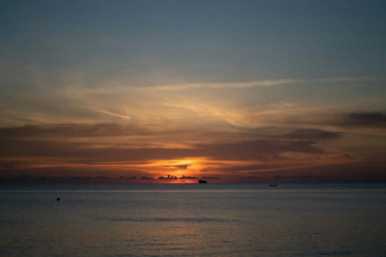 the sun setting over the water near the shore