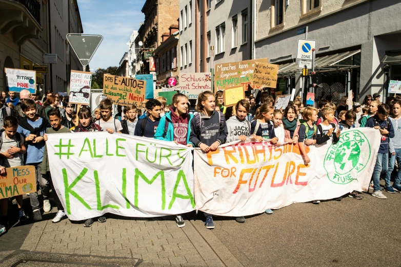 many people walking down the street while holding signs