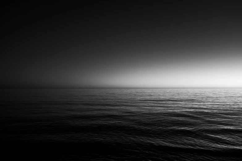 a lone boat in a calm ocean on a dark and overcast day