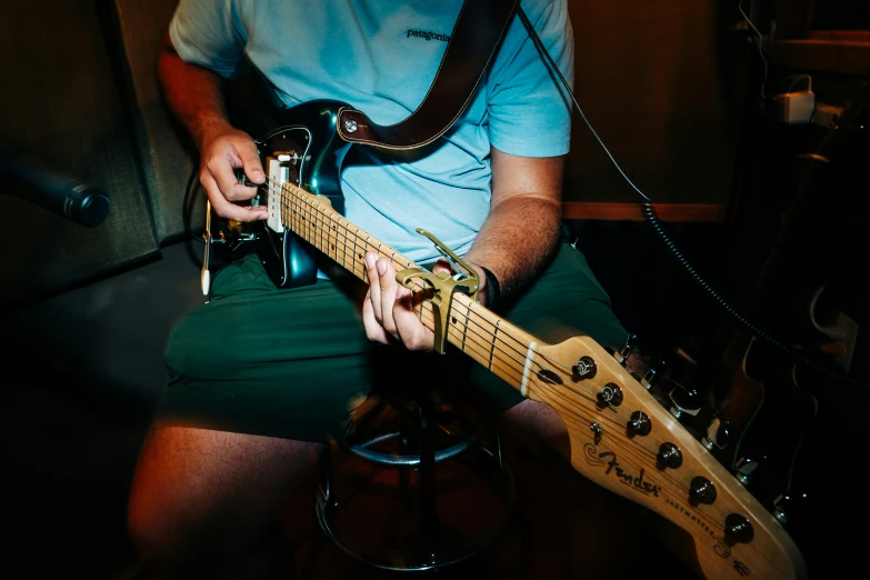 a man sitting in a chair playing on an electric guitar