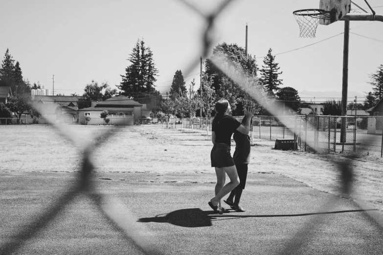 a woman and boy on a road with an overhand basketball hoop