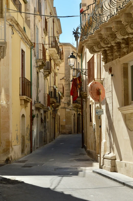 a narrow street with buildings and clothes on clothes lines