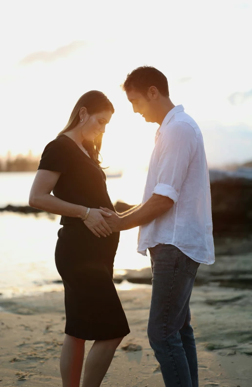 a couple holding hands on the beach during sunset